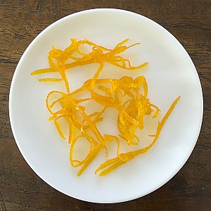 Kandierte Orangenzesten auf kleinem Teller präsentiert